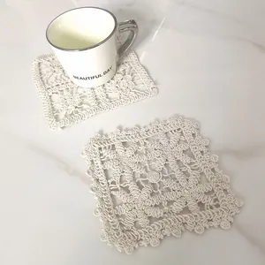 Detailed view of handmade vintage lace square cotton coaster on marble tabletop