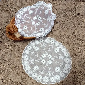 Close-up of white floral lace coaster with delicate embroidery on mesh background