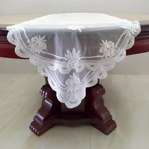 Dettaglio del ricamo in pizzo bianco e dei motivi floreali su un runner da tavola