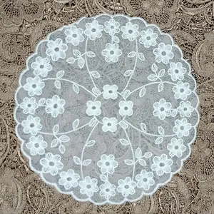 Detail view of round white lace coaster with delicate floral embroidery and mesh base