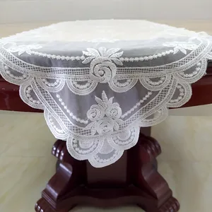Dettaglio di un runner da tavola in pizzo bianco con delicati ricami floreali