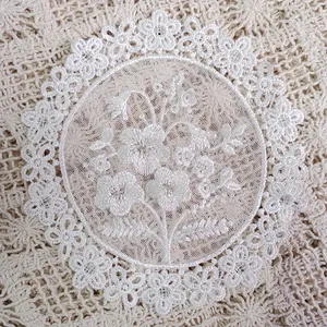 Close-up of white circular organza coaster with intricate floral embroidery details