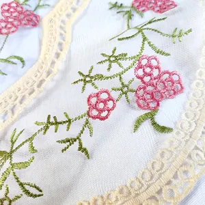 Gros plan de broderie florale sur tissu en maille blanche avec dentelle.