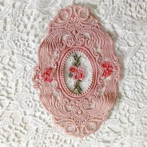 Detailansicht des rosa ovalen Spitzen-Untersetzers mit feiner Rosenstickerei.