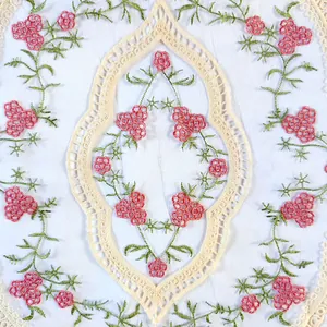 Vue détaillée de la broderie florale colorée sur tissu de nappe en dentelle blanche