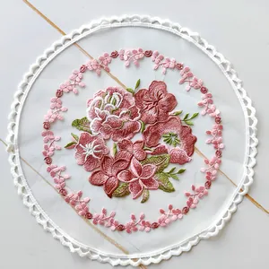 Detailed close-up of a round floral embroidered place mat on sheer mesh
