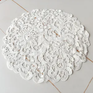 Detailed macro view of white elegant lace embroidered round placemat with floral pattern