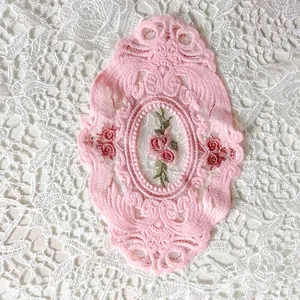 Detailansicht eines rosa ovalen Spitzenuntersetzers mit zarter Rosenstickerei auf Netz