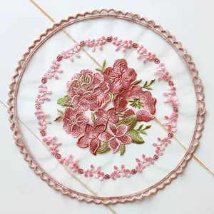 Detailed view of floral embroidery on a round pink mesh coaster with scalloped edges