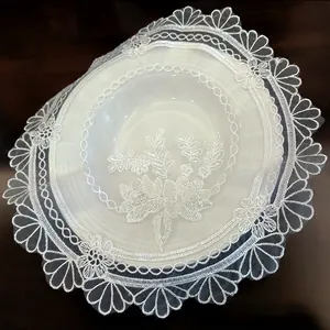Detailed view of a white circular lace placemat featuring elegant floral embroidery patterns