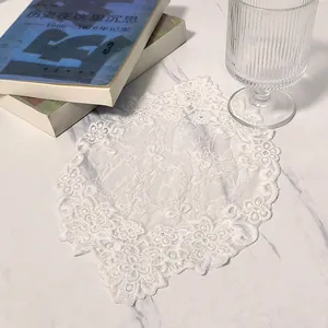 Close-up detail of a white floral lace coaster with delicate embroidery and mesh texture