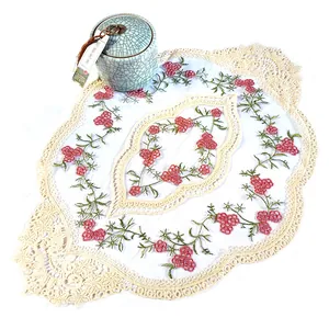Vue détaillée du napperon brodé de fleurs avec d'élégantes bordures en dentelle crème