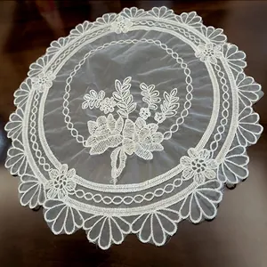 Close-up of white circular embroidered lace placemat with delicate floral patterns