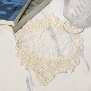 Detailed close-up of an off-white circular lace coaster with delicate floral embroidery