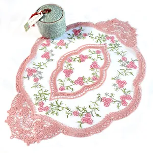 Gros plan détaillé du chemin de table en dentelle brodée rose à motifs.