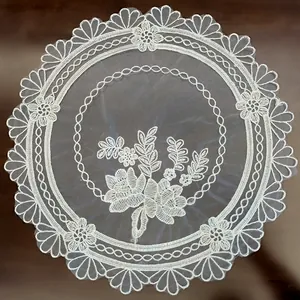 Close-up detail of intricate floral embroidery on a white European round lace placemat