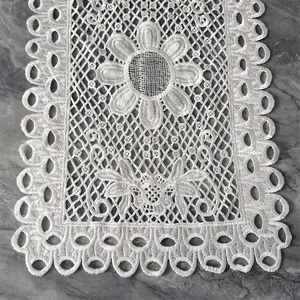 Detailansicht eines weißen bestickten Tischsets aus Spitze mit durchbrochenem Blumenmuster