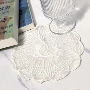 Close-up detail of white embroidered floral lace coaster with delicate mesh texture