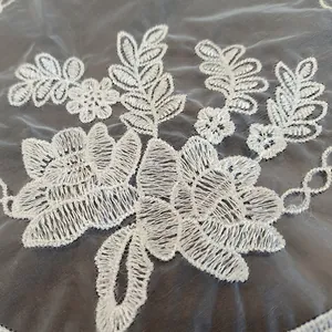 Close-up detail of intricate white floral embroidery on transparent mesh lace placemat