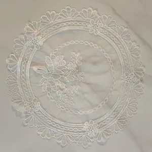 Elegant white circular lace placemat featuring intricate floral embroidery on marble
