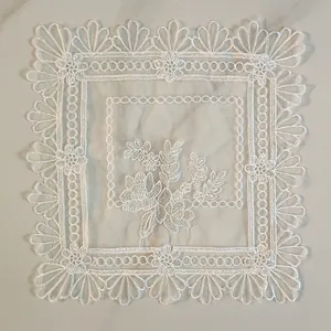Detail of white embroidered lace placemat with intricate floral patterns and elegant scalloped edges