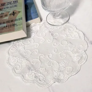Detailed macro view of white circular lace doily showing intricate floral embroidery patterns