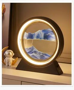 Lámpara de mesa circular con arte de arena movediza azul y anillo de luz LED cálida.