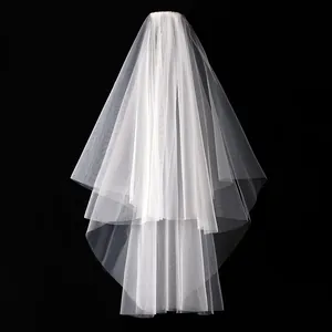 Elegante velo de novia blanco corto de dos capas con peine de metal sobre fondo negro.
