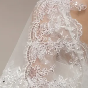Close-up of white wedding veil featuring intricate lace embroidery and sparkling sequins.