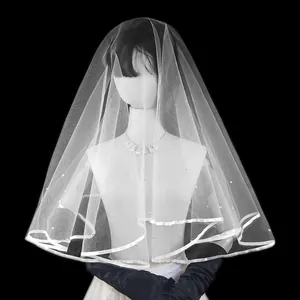 Vista detallada de velo de novia de una capa con borde de cinta y perlas en un maniquí