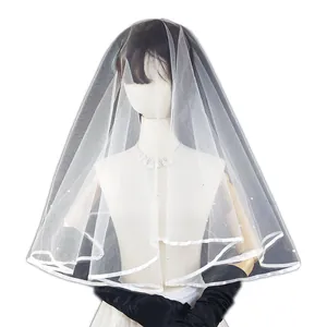 Detalle de cerca de un velo de novia blanco con borde de cinta y perlas en un maniquí.