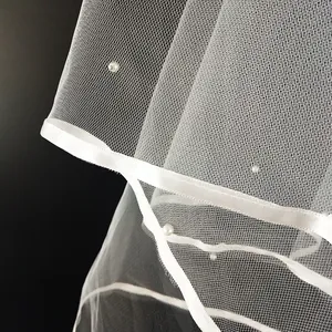 Vista detallada del velo de novia blanco de una capa con borde de cinta de raso y perlas