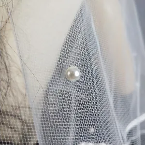 Primer plano detallado de una delicada perla en un velo de novia de tul blanco