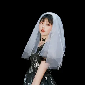 Primer plano de un velo de novia blanco corto de dos capas en una modelo con fondo negro