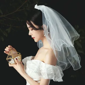 Elegant white short bridal veil with pearls and bow detail for wedding photography
