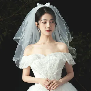 Elegant double-layered short white bridal veil featuring pearl accents and a silk bow headpiece