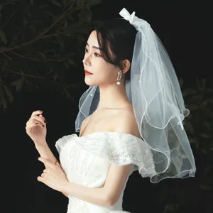 Close-up of a minimalist white bridal veil with a delicate bow on an elegant bride.