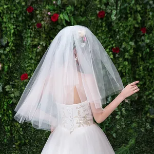 Vue arrière d'un voile de mariée court en tulle souple blanc sur mur de fleurs
