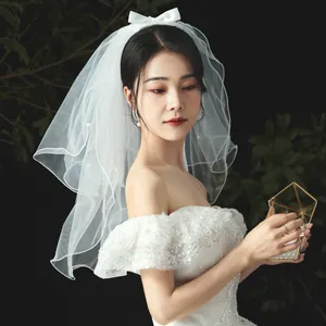 Elegant short white bridal veil featuring a chic silk bow and delicate pearl accents