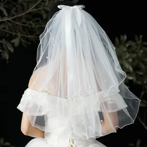 Detailed back view of short white bridal veil with pearls and ribbon bow decoration