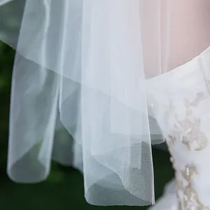 Détail d'un voile de mariée blanc doux avec une texture de filet et des couches