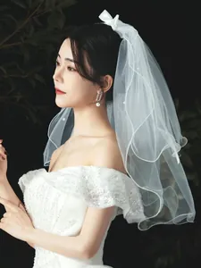 Detailed side view of short white bridal veil with pearls and bow decoration.