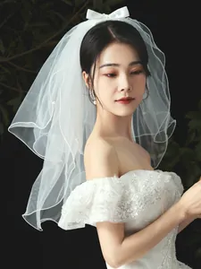 Detailed shot of a short white bridal veil featuring a satin bow and pearl accents