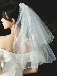 Detailed close-up view of a layered short white bridal veil with pearl embellishments