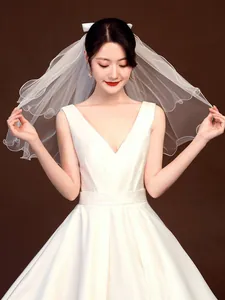 Close-up detail of an elegant short white bridal veil featuring a stylish bow ornament