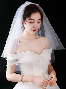 Detailed shot of double-layer white bridal veil with pearl-embellished wedding dress