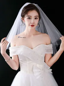 Elegant detail of a minimalist short white bridal veil featuring delicate sheer mesh fabric.