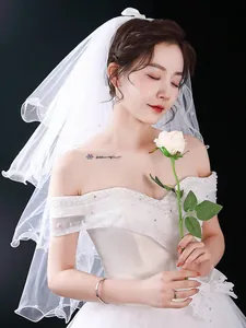 Detailed view of simple white bridal veil with pearl edge and elegant multi-layer design.