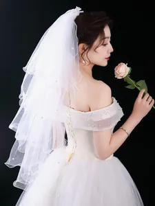 Detailed side view of an elegant tiered white bridal veil featuring pearl accents