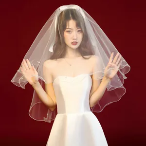 Elegant short white bridal veil with pearls worn by a model in a wedding dress
